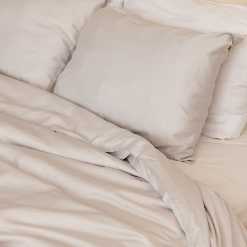 May include: A white duvet cover with a white pillow and a white pillowcase. The duvet cover is folded back to reveal the white sheets underneath.