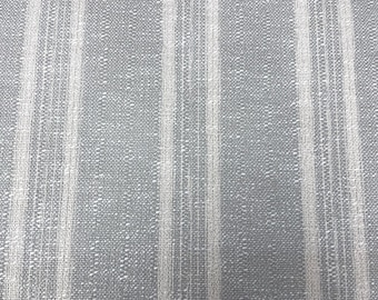May include: A woven fabric featuring a pattern of vertical stripes in shades of grey and white. The material displays a textured, cross-hatched weave with alternating thick and thin white lines running parallel against a solid grey background.