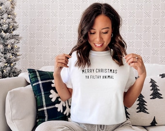 Könnte beinhalten: Weißes T-Shirt mit schwarzem Text, der "Frohe Weihnachten Ya Filthy Animal" lautet.