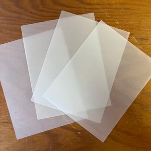 May include: Three sheets of translucent white paper, stacked on top of each other.