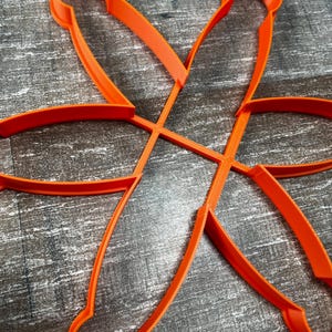 Peut inclure: Emporte-pièce orange vif en forme de fleur. Le découpoir est en plastique et comporte six pétales incurvés, chacun avec une poignée arrondie. Idéal pour faire des biscuits ou autres pâtisseries.