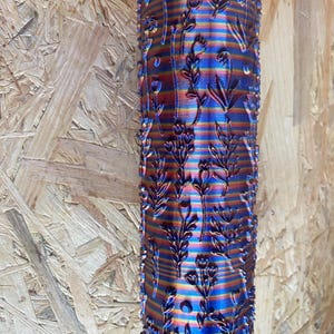 Può includere: Un rullo per pittura blu e arancione con un motivo floreale. Il rullo è realizzato in un materiale strutturato e ha una forma esagonale.