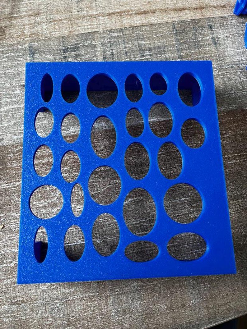 May include: A bright blue foam insert with various oval and circular cutouts. The cutouts are of different sizes and shapes, arranged in a grid pattern. The insert is designed to hold small objects, likely for organization or display.