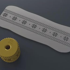 Pode incluir: Um objeto alongado cinza claro com um padrão de floco de neve e um objeto circular amarelo com um buraco no centro. O padrão de floco de neve está ao longo da borda superior do objeto cinza. O objeto amarelo tem o texto "3Dmon".