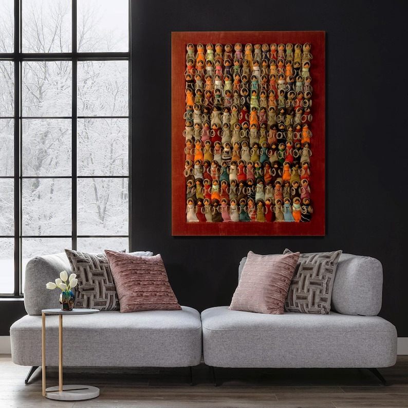Pu&ograve; includere: Un'opera d'arte incorniciata che presenta un mosaico colorato di piccole figure di bambole disposte in una griglia. Le figure sono fatte di tessuto e hanno colori, motivi e design diversi. La cornice &egrave; di colore rosso scuro.