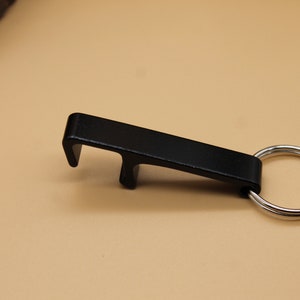 May include: A black metal bottle opener with a key ring attached.
