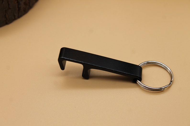 May include: A black metal bottle opener with a key ring attached.