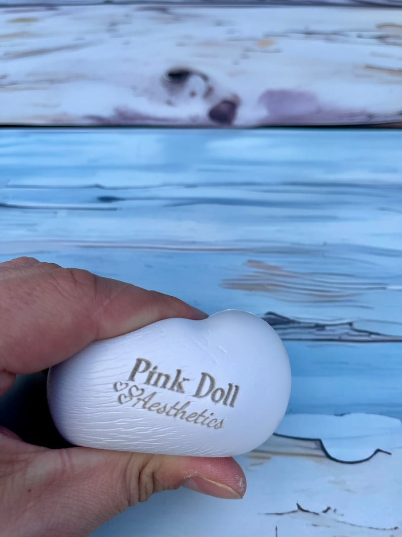 K&ouml;nnte beinhalten: Wei&szlig;er herzf&ouml;rmiger Stressball mit dem Aufdruck "Pink Doll Aesthetics".