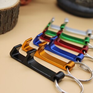 May include: A set of six keychains with bottle openers. The keychains are in different colors: black, gold, blue, red, green, and silver.