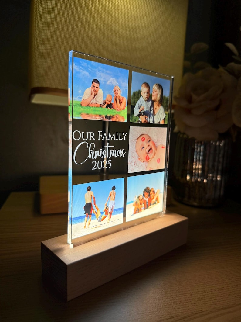 Puede incluir: Un expositor de fotos de acr&iacute;lico transparente con seis fotos familiares, montado sobre una base de madera. El texto "OUR FAMILY Christmas 2025" est&aacute; impreso en la parte delantera. Las fotos muestran a miembros de la familia en varios entornos.