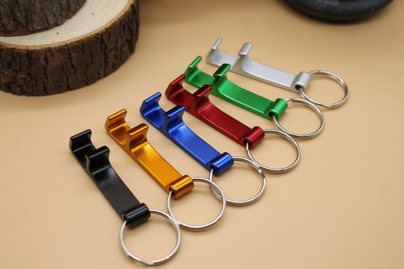 May include: Six different colored bottle openers with key rings. The colors are silver, green, red, blue, gold, and black.
