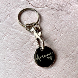 May include: Silver keyring with a round tag that says "Ariana" with two hearts.