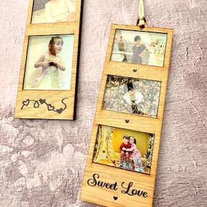 May include: Wooden photo frame with three rectangular openings, each holding a photograph. The frame is engraved with hearts and the words "Sweet Love." A beige string is attached for hanging. The frames are made of light-coloured wood.