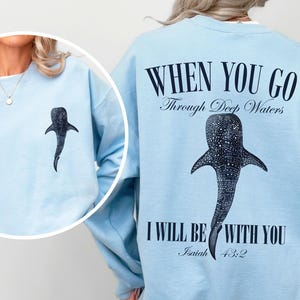 May include: Light blue sweatshirt with a whale shark graphic and the text "WHEN YOU GO Through Deep Waters I WILL BE WITH YOU Isaiah 43:2".
