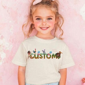 A young girl with a pink bow in her hair is smiling and wearing a white t-shirt with the word "CUSTOM" printed on it.