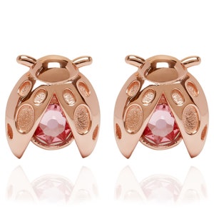 May include: A pair of rose gold ladybug earrings with pink crystal accents.