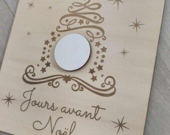 Puede incluir: Un calendario de adviento de madera con un círculo blanco en el centro. El calendario presenta un árbol de Navidad estilizado con estrellas y el texto "Elio & Adelia" y "Jours avant Noël".