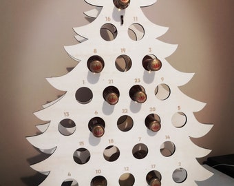 Puede incluir: Un soporte para botellas de madera con forma de árbol de Navidad con 24 ranuras numeradas para botellas. El árbol está hecho de madera clara y tiene una estrella en la parte superior.