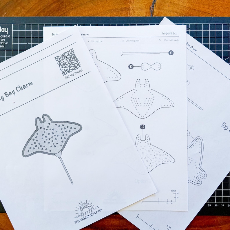 May include: White paper templates for a bag charm, with a stingray design and dotted patterns. The templates include diagrams, measurements in centimetres, and the website Nomadecrafts.com.