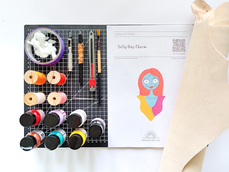 May include: A leathercraft pattern for a Sally Bag Charm from Nightmare Before Christmas. The pattern includes a color illustration of Sally, a QR code, and the text "Get the Tutorial". The image also shows a variety of craft supplies, including leather, paint, thread, and tools.