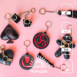 May include: A set of eight leather keychains with various designs, including a spade, a heart, a circle with a symbol, a figure, and a buckle. The keychains are black with red stitching and gold accents. The keychains are displayed on a pink background with file format labels.
