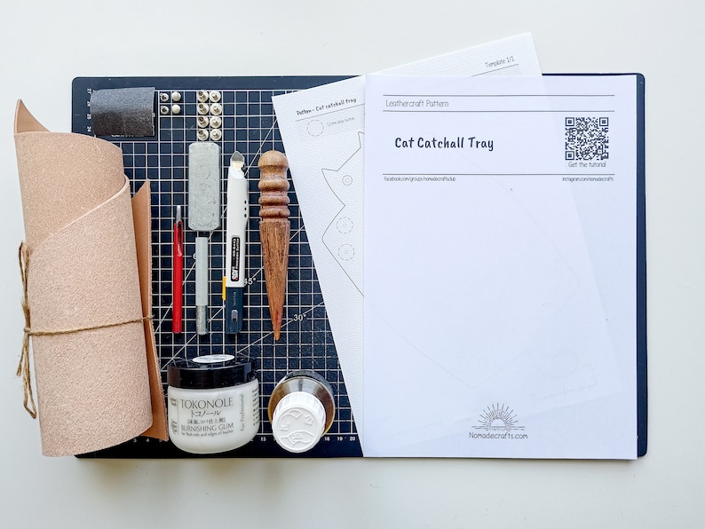May include: A leathercraft kit for making a cat catchall tray. The kit includes a piece of leather, a leathercraft pattern, a leather stitching awl, a leather punch, a leather skiver, a leather burnishing cream, a leather glue, a sanding block, and a self-healing cutting mat.