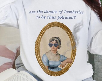 May include: White long-sleeve sweatshirt featuring an oval portrait of a woman wearing heart-shaped sunglasses. The portrait is in a gold frame. The text "Are the shades of Pemberley to be thus polluted?" is above the portrait.