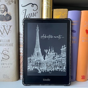 May include: A black and white illustration of the Eiffel Tower and Parisian buildings on a Kindle e-reader. The text "Adventure awaits..." is displayed on the screen.