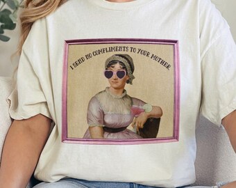 May include: A white t-shirt with a graphic print of a woman wearing heart-shaped sunglasses and holding a cocktail. The text on the graphic reads "I send no compliments to your mother."