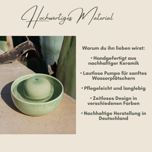 Op de afbeelding: Een lichtgroene keramische fontein met een ronde, appelvormige bovenkant, in een grotere kom. De afbeelding bevat Duitse tekst: "Hochwertiges Material" en opsommingstekens die de kenmerken van het product beschrijven.