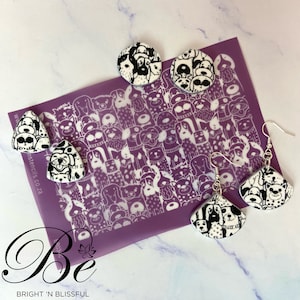 May include: Black and white dog-themed earrings and stud earrings. The earrings and studs feature a repeating pattern of various dog breeds. A purple stencil with a dog illustration is in the background.