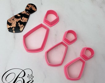Könnte beinhalten: Satz mit vier rosafarbenen Plastik-Ausstechern in Form einer Krawatte. Die Ausstecher sind in einer Reihe vom größten zum kleinsten angeordnet.