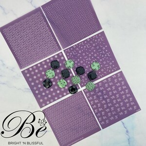 Könnte beinhalten: Sechs violette Schablonen mit weißen Mustern, darunter Punkte, Linien und geometrische Formen. Die Schablonen sind in einem Raster angeordnet und von neun kleinen grünen und schwarzen Keramikfliesen umgeben.