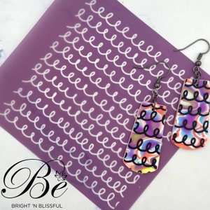 May include: A pair of colourful dangle earrings with a swirl pattern. The earrings are made of polymer clay and have silver hooks. The earrings are shown on a purple background with a white swirl pattern.