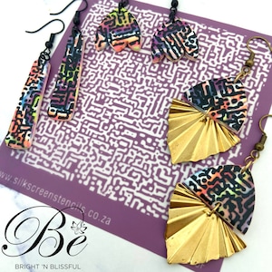 May include: A collection of colorful earrings with abstract patterns. The earrings feature a mix of shapes, including long rectangles, petal-like designs, and fan-shaped gold metal. The background includes a purple stencil with a white pattern and the text "Bright 'n Blissful".