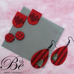 May include: Red and black patterned earrings and matching accessories. The earrings are teardrop-shaped with a small green tree design. Other accessories include two pairs of round earrings and two rectangular pieces. The image also includes the text "Be Bright 'n Blissful".