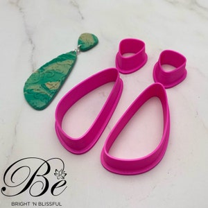 Könnte beinhalten: Satz mit vier rosa Polymer Clay-Ausstechern in Tropfenform. Die Ausstecher werden verwendet, um Ohrringe oder anderen Schmuck herzustellen.
