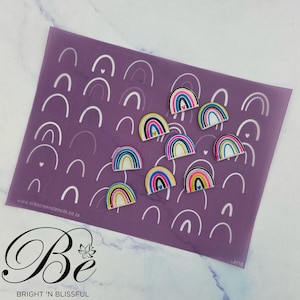May include: Purple stencil sheet with white rainbow outlines and colourful rainbow cutouts. The stencil sheet has the text "www.silkscreenstencils.co.za" and "Be BRIGHT 'N BLISSFUL" printed on it. The sheet is labelled "LAY10".