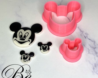 May include: A selection of Mickey Mouse-themed cookie cutters and decorative pieces. The cutters are bright pink, and the decorative pieces feature black and white Mickey Mouse faces. The logo "Bright 'N Blissful" is visible in the bottom left corner.
