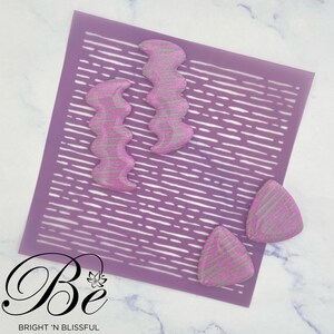May include: Three pink and silver glitter resin earrings in the shapes of a wavy rectangle and two triangles. The earrings are on a purple background with a white pattern.