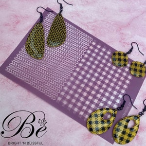 May include: A selection of earrings with black hooks, featuring yellow and black patterns. The earrings are presented on a purple stencil with a white design. The image also includes the text "Be" and "BRIGHT 'N BLISSFUL".