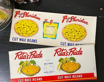 May include: Two vintage labels for canned cut wax beans. The top label is for "Pride of Sheridan" brand and the bottom label is for "Rita's Pride" brand. Both labels feature a bowl of yellow cut wax beans.