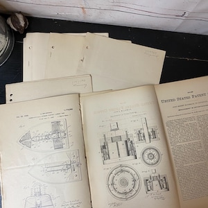 May include: Vintage patent documents, including diagrams of an electric iron and piston packing, are displayed open on a dark surface. The pages are aged with visible wear and tear, showcasing detailed technical illustrations and text.