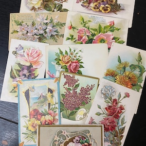 Puede incluir: Una colecci&oacute;n de postales florales vintage. Las postales presentan varios arreglos florales, incluyendo rosas, pensamientos y lilas, en tonos rosa, amarillo, morado y rojo. Algunas tarjetas tienen bordes decorativos y texto.
