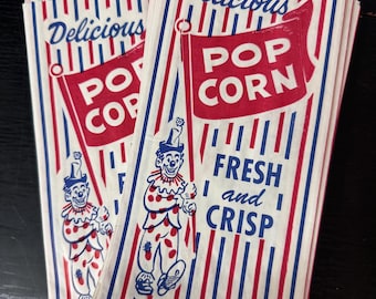 May include: A stack of vintage popcorn bags with red and blue stripes. The bags feature a clown illustration and the text "Delicious Pop Corn Fresh and Crisp".
