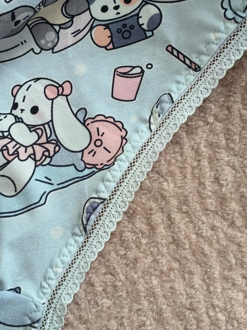 May include: Light blue underwear with a white lace trim and a cartoon animal print. The print features a variety of animals, including a dog, a cat, and a rabbit. The underwear has a light blue background with white polka dots.