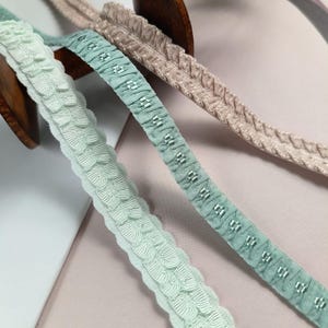 May include: Three different types of decorative trim with ruffled edges. The trim is in shades of green and beige.