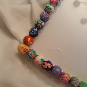 May include: A close-up of a colorful beaded frame with a variety of floral patterns. The beads are strung on a clear wire and are arranged in a rectangular shape.