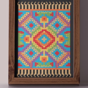 Könnte beinhalten: Ein gerahmtes Kunstwerk mit einem bunten, pixelartigen Teppich mit geometrischem Muster. Der Teppich ist hauptsächlich blau, gelb, orange und rot mit schwarzen und weißen Akzenten.