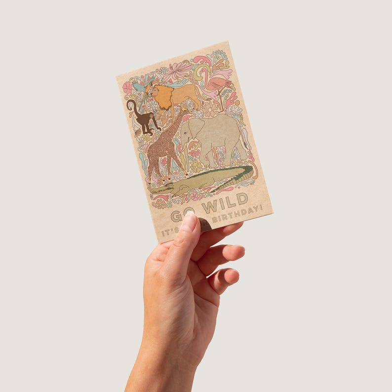 K&ouml;nnte beinhalten: Rechteckige Geburtstagskarte mit braunem Hintergrund und dem Text "GO WILD BIRTHDAY!". Sie zeigt Illustrationen eines L&ouml;wen, Affen, Giraffe, Elefanten und Krokodils. Die Karte hat ein farbenfrohes Blumenmuster.